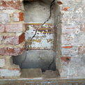 Ein Loch in der Vermauerung macht die Wandmalereien sichtbar. © 2023 Tilo Schöfbeck